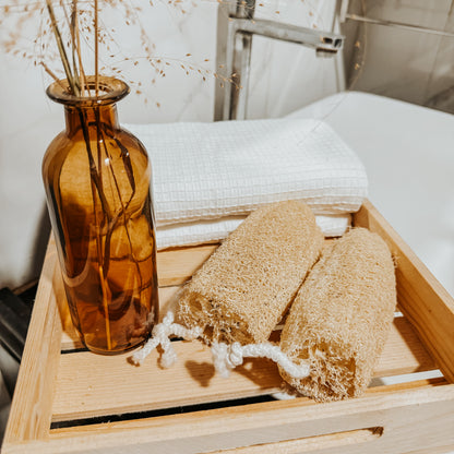 Two Jaivik Store organic straight loofah bath scrubbers on a wooden tray, showcasing natural skincare essentials