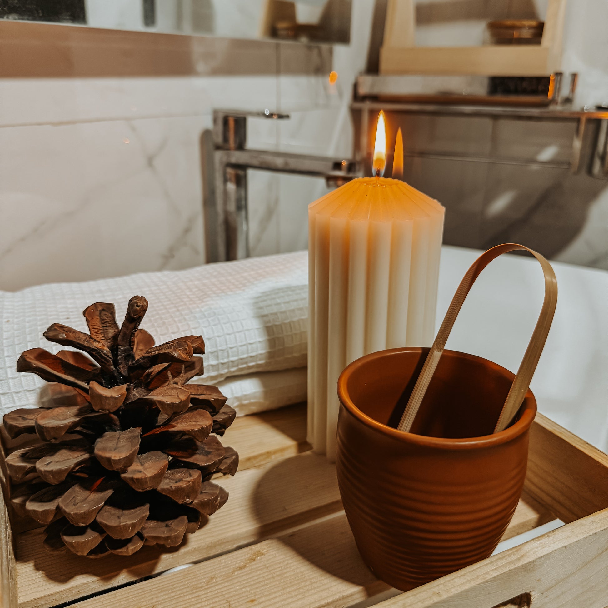 Jaivik Store bamboo tongue cleaner on a wooden tray with a pine cone and candle, showcasing sustainable oral care