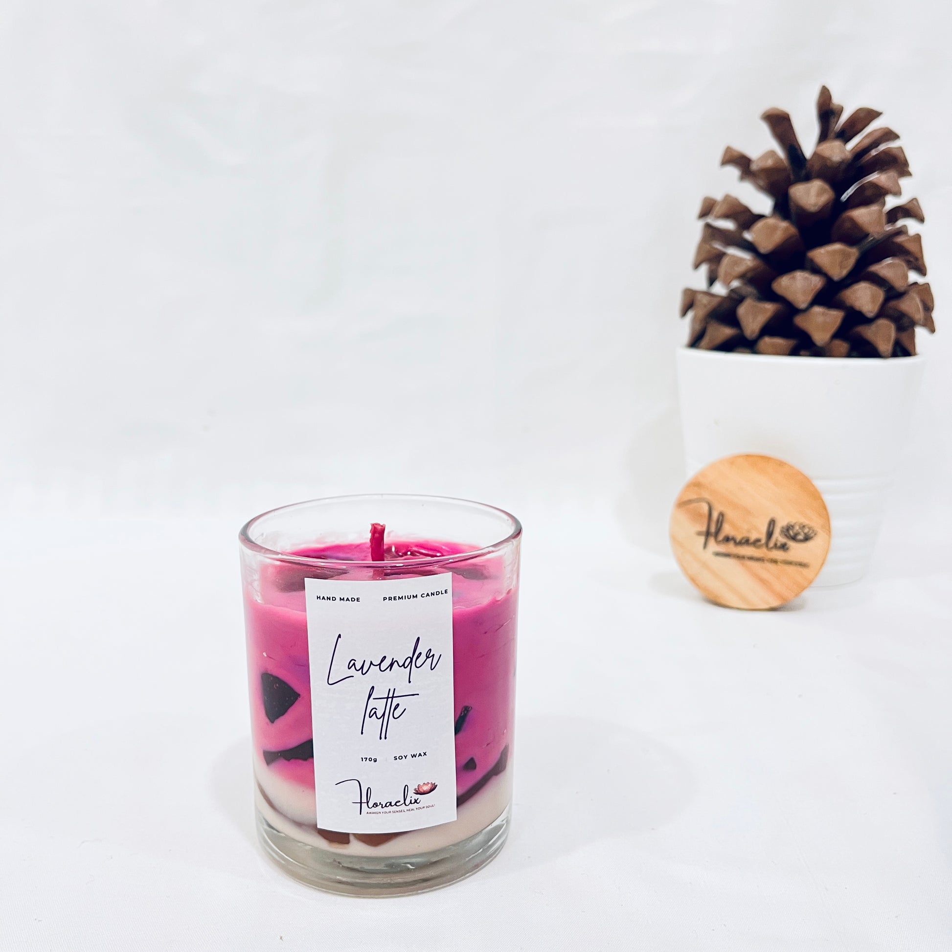 Jaivik Store Aromatic Lavender Lattee luxury soy wax candle, 180g, surrounded by a serene pine fruit backdrop for a peaceful vibe