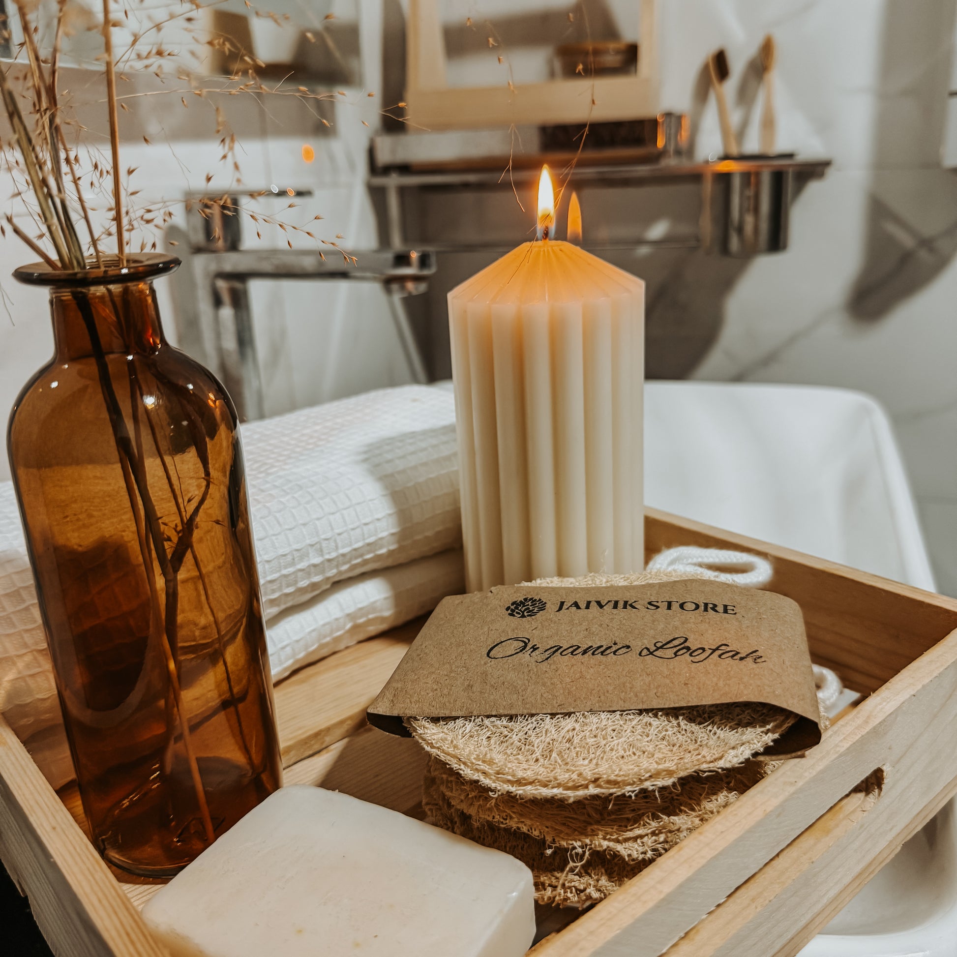 Jaivik Store organic round loofah bath scrubber with wooden tray, towel, and candle, creating a relaxing bath atmosphere