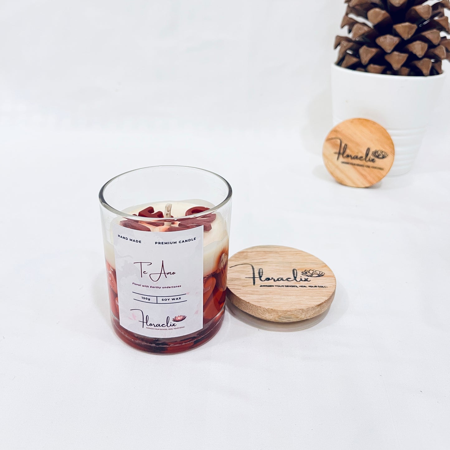 Jaivik Store Te Amo soy wax jar candle, 150g, with lid open, set against a pine fruit backdrop for natural elegance